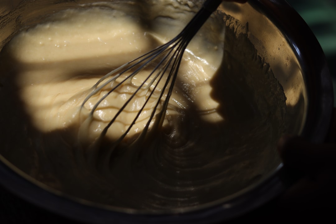 Whisk mixing a creamy sauce in a bowl.