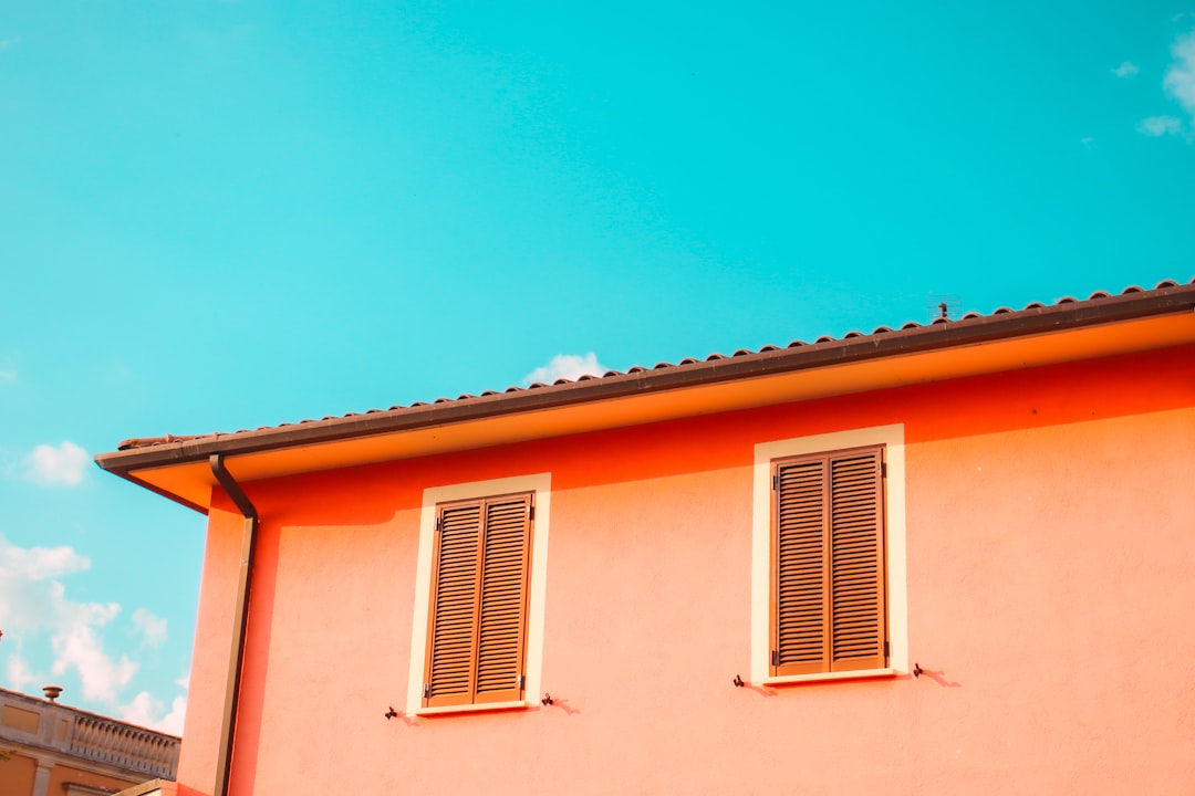 a pink building with two windows and a sky background